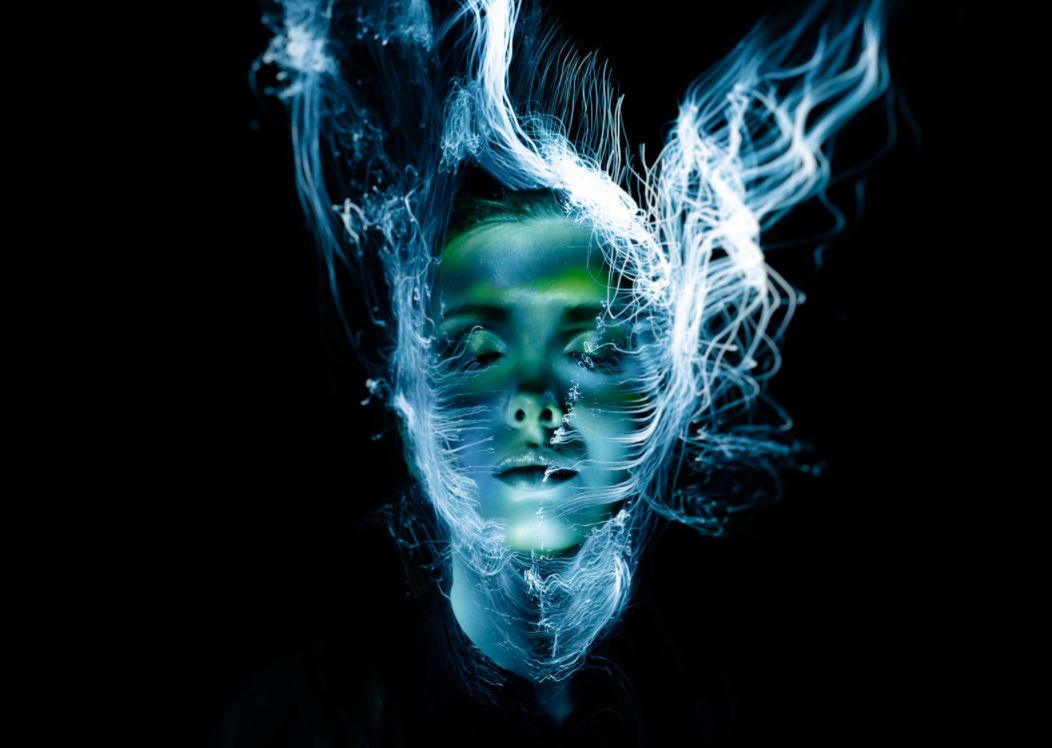 visage d'une femme sur fond sombre avec des flux d'énergie lui traversant le visage